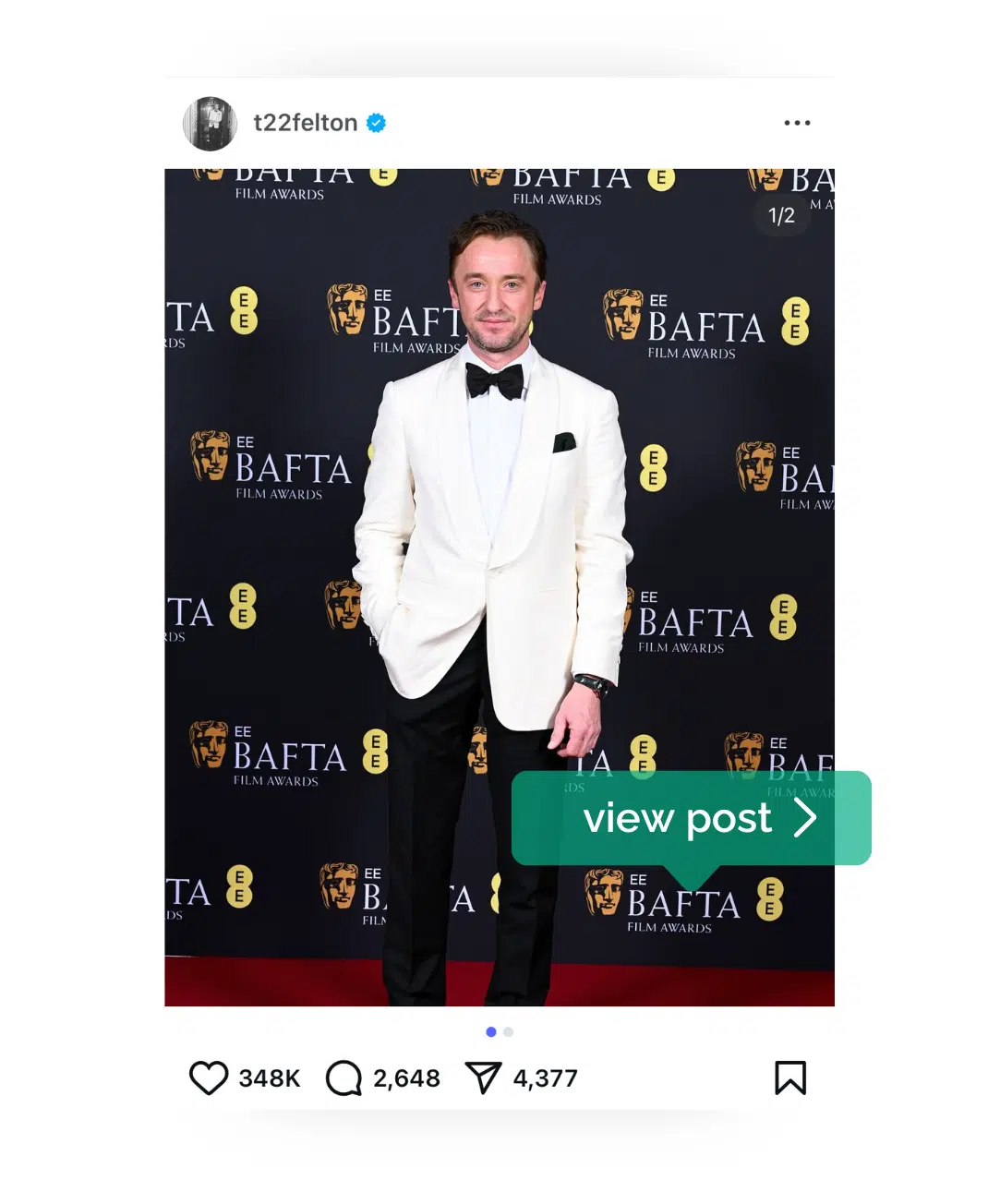 An Instagram Image of Tom Felton in a white tux, black trousers and bowtie, with his hand in his pocket, against a BAFTA backdrop with an Omega watch on his other hand. 